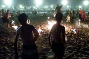 Dos niños observan como varios jovenes saltan una hoguera durante la celebración anoche en la playa de Las Arenas de Valencia de la Noche de San Juan. EFE/Manuel Bruque. (Imagen Digital)[IMAGEN DIGITAL]