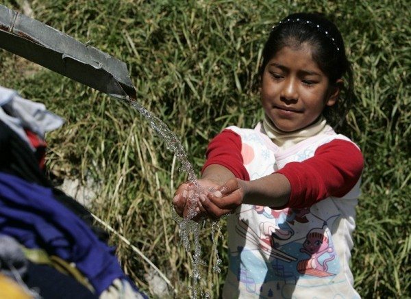 Una niña boliviana recibe agua de una vertiente.EFE/Martin Alipaz