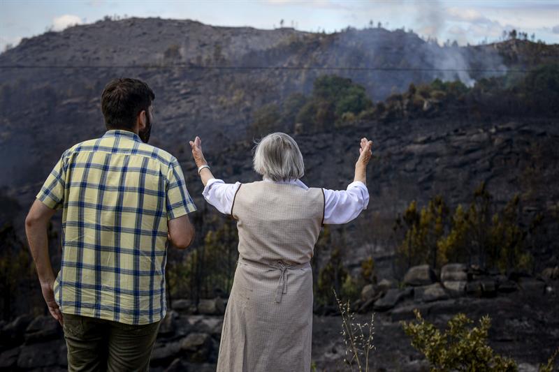 Unos vecinos del pueblo de Naves (Palmés) ante la superficie calcinada. EFE/Brais Lorenzo