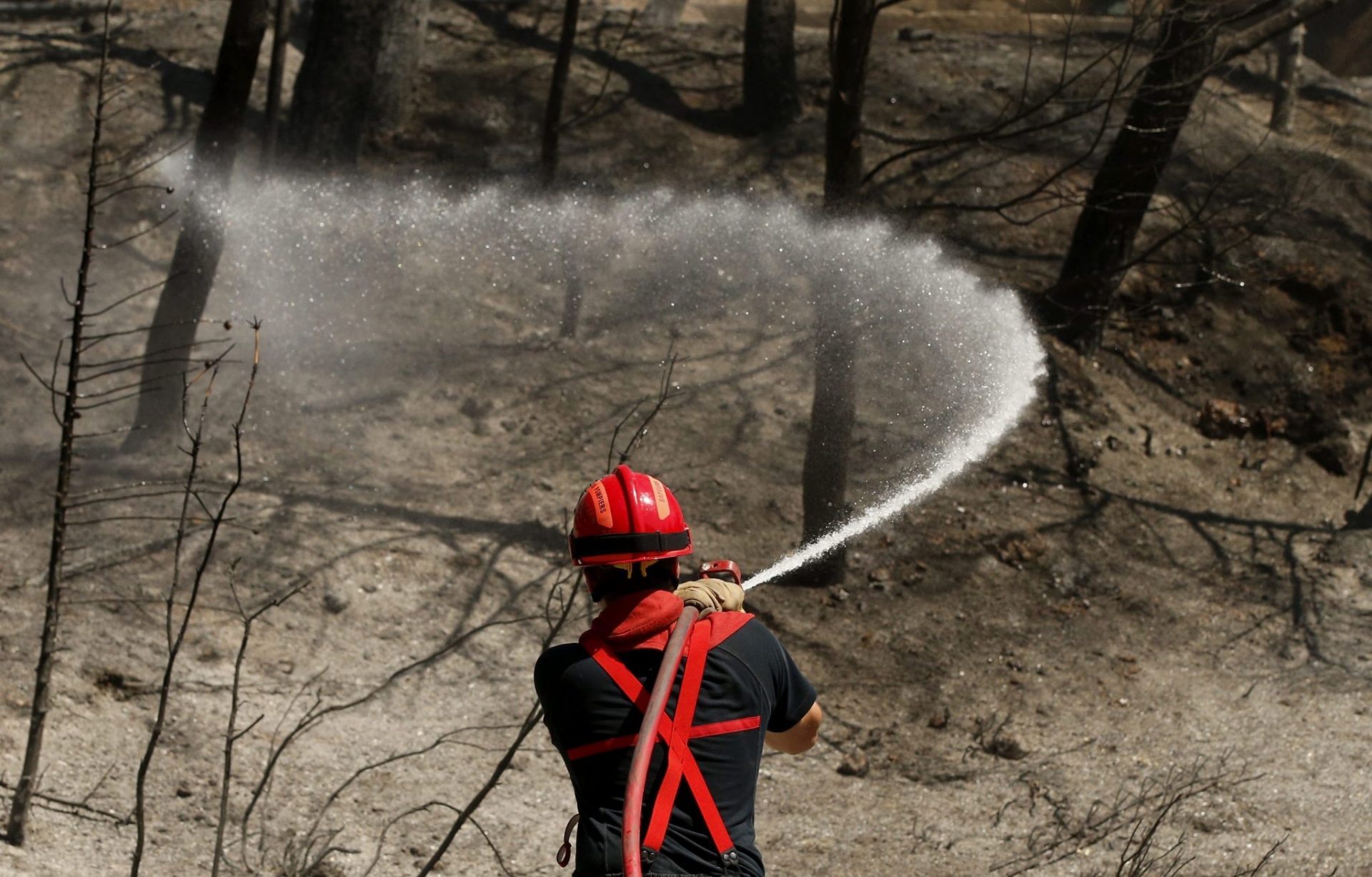 Un bombero galo refresca una zona quemada en los alrededores de la localidad de Vitrolles, cerca de Marsella, en el sur de Francia, hoy. EFE/Guillaume Horcajuelo