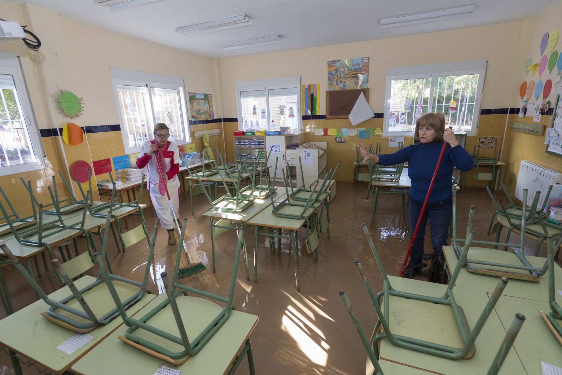 Dos trabajadoras de la limpieza retiran este martes el agua del aula de un colegio, tras las inundaciones causadas por las intesas lluvias caídas en los municipios del mar Menor este fin de semana. EFE/Marcial Guillén