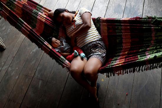 Puerto América (Perú), 10/11/2018.- Una madre descansa junto a su hija en Puerto América a orillas del río Morona, afectado en 2016 por el vertido de petróleo procedente del oleoducto de Petroperú en la Amazonia peruana. Los pueblos de la Amazonia peruana se sienten abandonados y siguen sufriendo las consecuencias de los derrames de petróleo que en 2016 tiñeron de negro los ríos donde pescan y se bañan y las tierras donde cultivan yuca, maíz y maní, base de su alimentación. EFE/Chema Moya