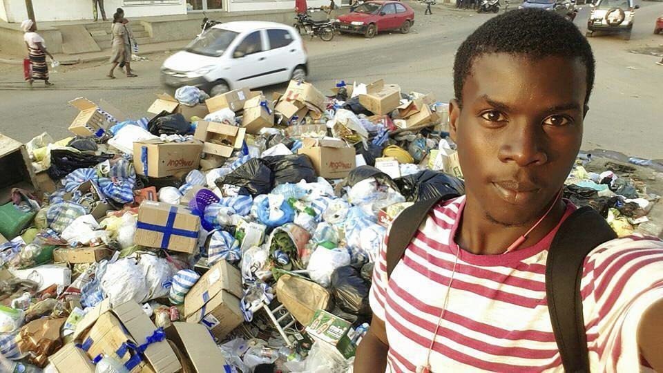 Un joven se hace un selfi delante de un montón de basura en una calle de Luanda.