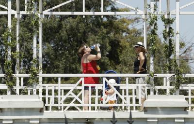 Una mujer toma agua para rebajar el calor en  parque Rosedal de Buenos Aires.