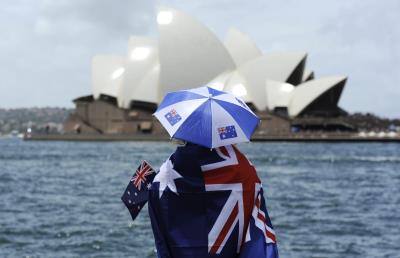 Una mujer cubierta con la bandera australiana frente al Teatro de la Ópera de Sídney (Australia) en una foto de archivo.