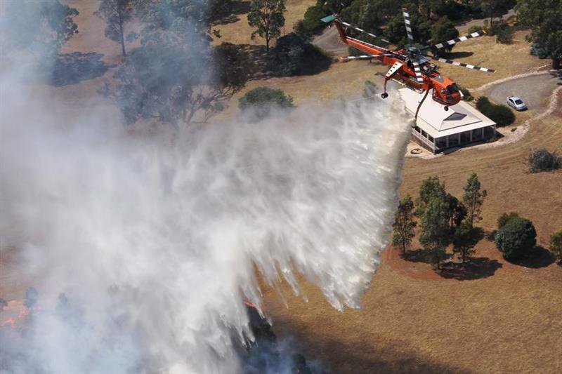 Vista aérea de un helicóptero soltando agua sobre una zona de Australia asolada por los incendios forestales.