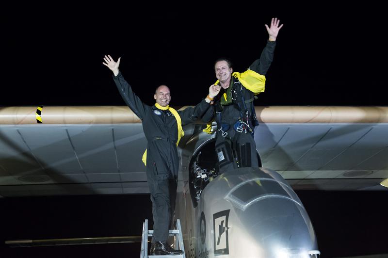 los pilotos Bertrand Piccard (i) y André Borschberg (d) saludando sobre el prototipo de avión movido únicamente por energía solar