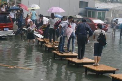 Vecinos utilizan mesas para cruzar una calle inundada en Wuhan.