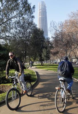  dos personas circulando con su bicicleta por una vía de Santiago, Chile.