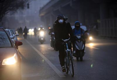 Un ciclista utiliza mascarilla mientras circula en bici por una calle de Pekín (China) a consecuencia de la contaminación.