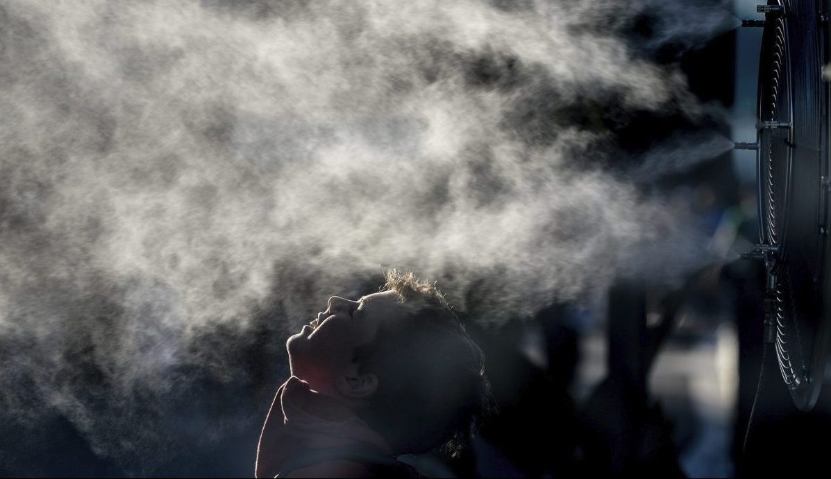 Una persona combate el calor con un ventilador que rocía agua.EFE/Filip Singer