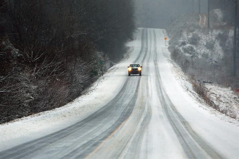 Un vehículo avanza por una carretera cubierta de nieve 