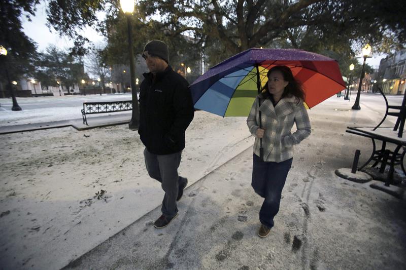 Dos personas caminan por una calle cubierta de nieve en Mobile, Alabama (EE.UU.)