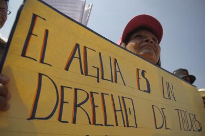 Un salvadoreño porta una pancarta en la que se lee "El agua es un derecho de todos".