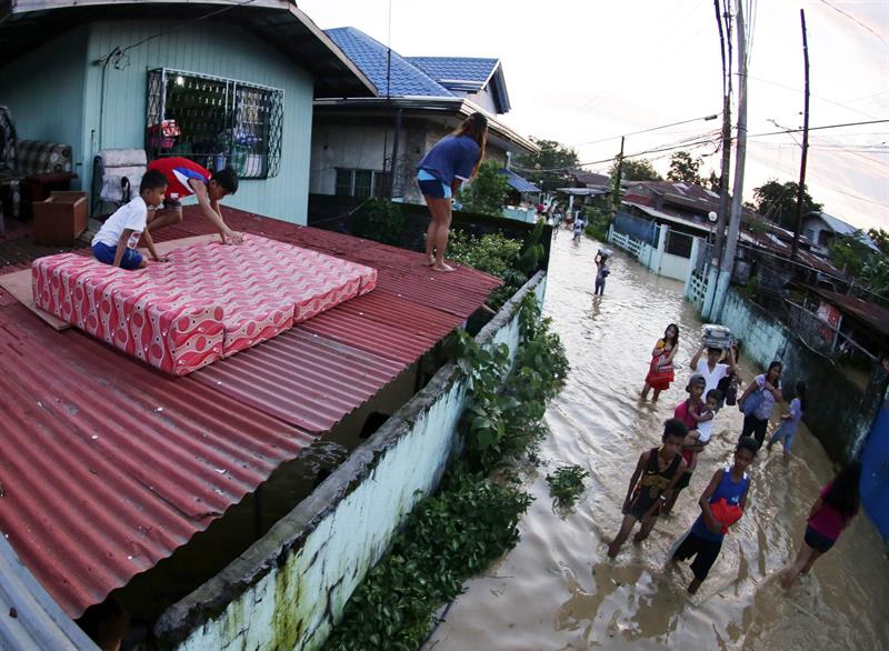 Una familia rescata algunas de sus pertenencias de su casa anegada en Calumpit en la provincia de Bulacan, 