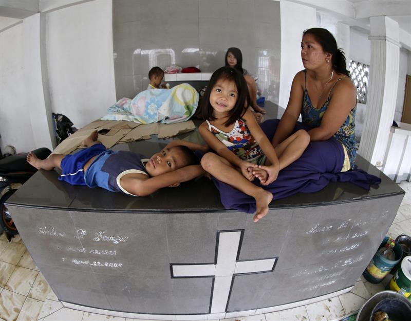 Una familia se pone a salvo de las inundaciones sobre una tumba del cementerio de Cabanatuan. 
