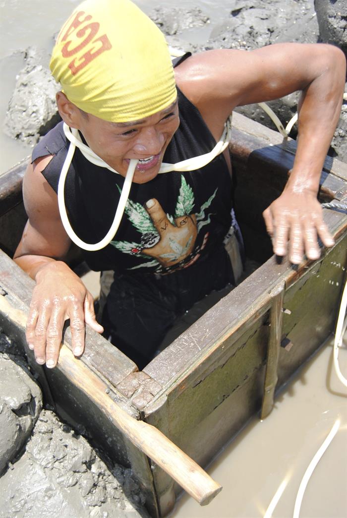 Un minero por donde se sumerge bajo las aguas y con el tubo de plástico que le permite respirar.