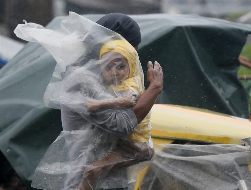Un residente protege a su hijo del fuerte viento y lluvia con un plástico por el paso del tifón Rammasun.   