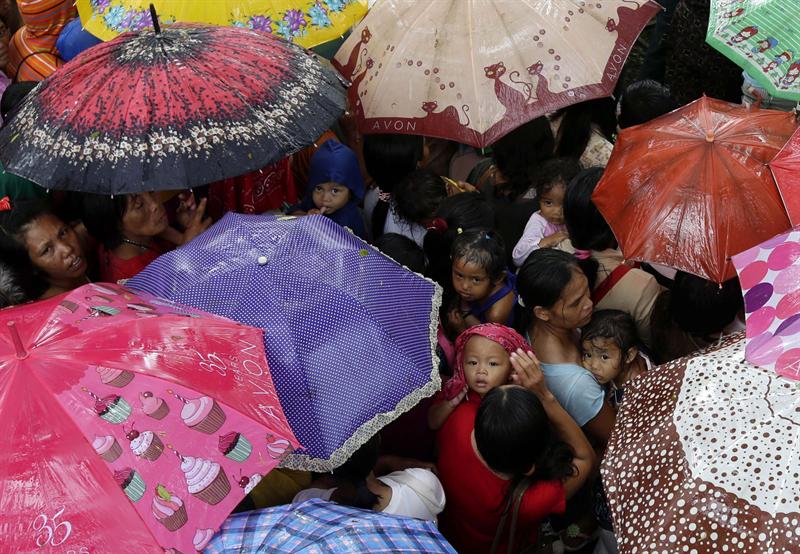 Decenas de personas evacuadas tras el terremoto de 7,2 grados se refugian de la lluvia mientras esperan a recibir alimentos en la localidad de Sagbayan (Filipinas), hoy, jueves 17 de octubre de 2013.