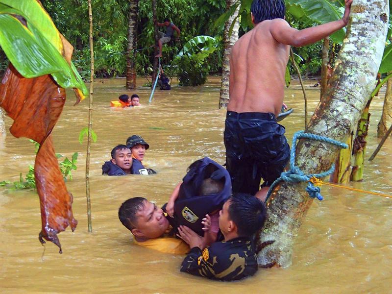 Miembros de un equipo de rescate evacuan a residentes tras el desbordamiento de un río en Isabela , al sur de Filipinas.