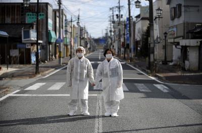 Con traje y máscara protectora, el matrimonio Yuzo Mihara posa para el fotógrafo en una calle desierta de la abandonada localidad de Namie, en la prefectura de Fukushima (Japón), en febrero de 2013. Namie se encuentra en el radio de 20km de exclusión alrededor de la planta nuclear.
