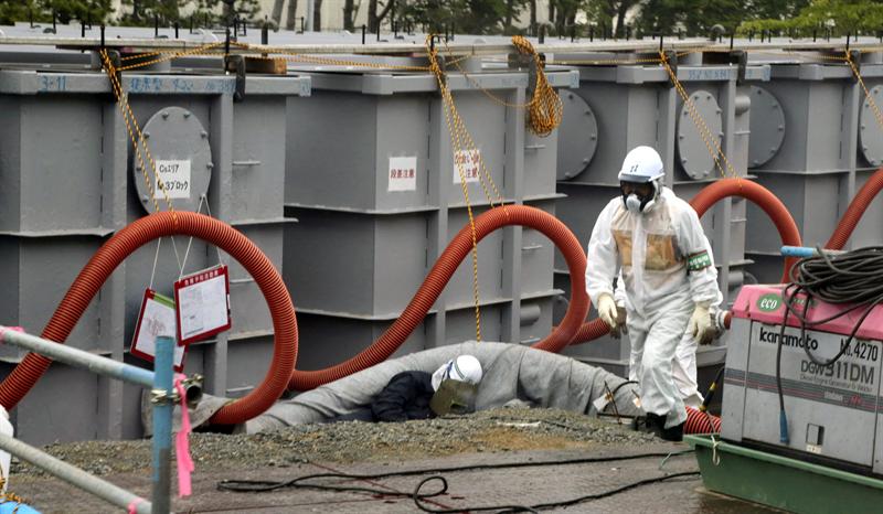 Una fotografía de archivo fechada el 12 de junio de 2013 muestra a un trabajador de la Tokyo Electric Power Company (TEPCO) vistiendo ropa protectora mientras trabaja alrededor de los tanques de agua en la central nuclear de Fukushima (Japón).