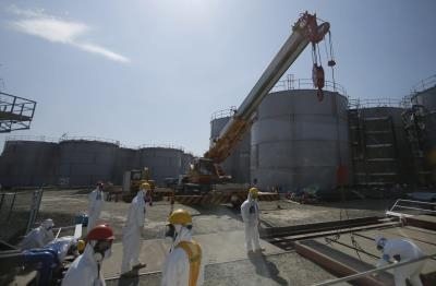 Operarios trabajan junto a los tanques de agua contaminada por la radiación, en la planta de TEPCO.