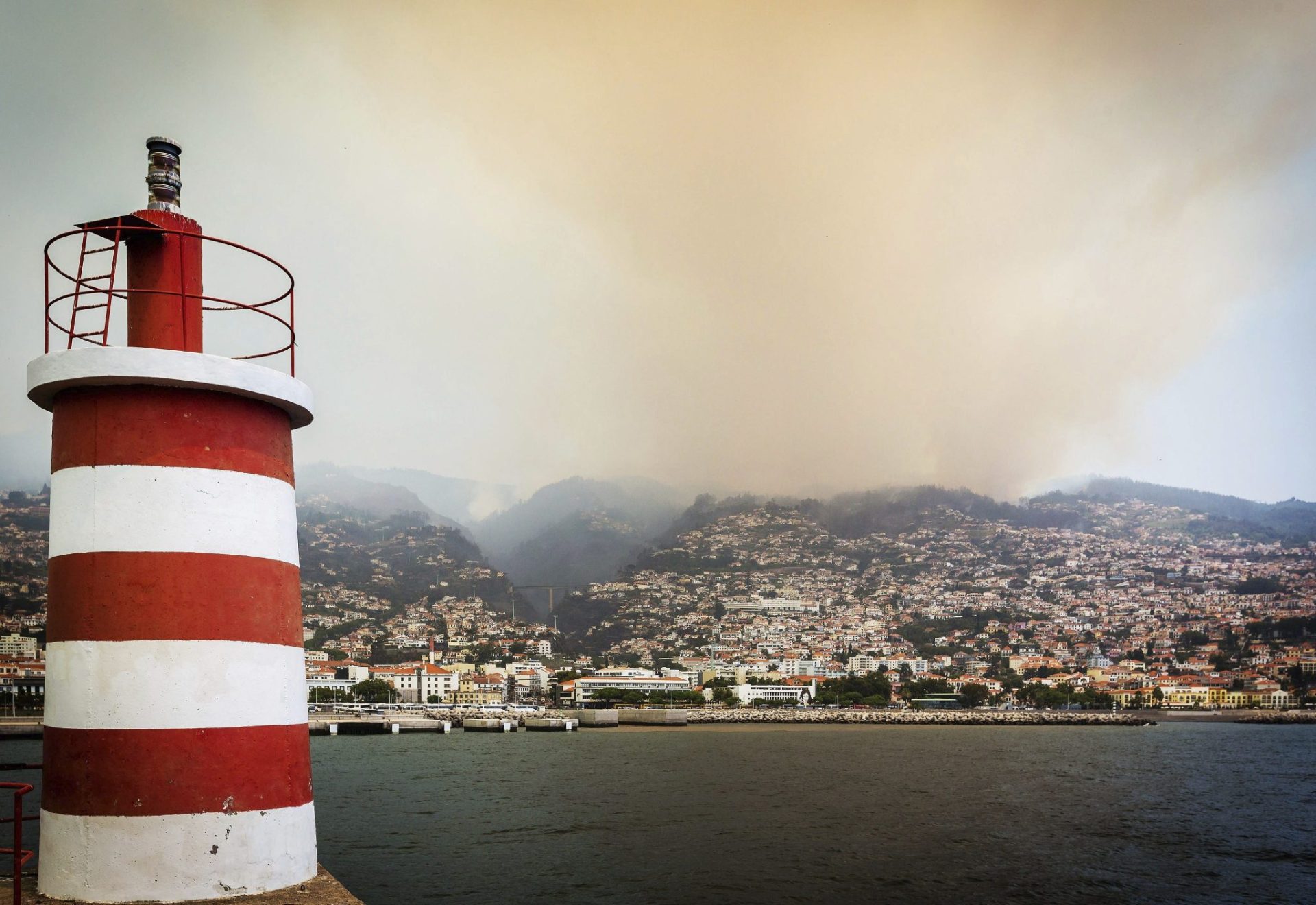 FUNCHAL (PORTUGAL) 10/08/2016.- Una columna de humo cubre el cielo de Funchal, isla de Madeira (Portugal) hoy, 10 de agosto de 2016. Los tres fallecidos en los incendios que azotan Funchal, la capital del archipiélago luso de Madeira, son de la misma familia y hay un total de 300 heridos hospitalizados, según confirmó hoy a Efe el alcalde de la ciudad, Paulo Cafofo. EFE/Homem De Gouveia