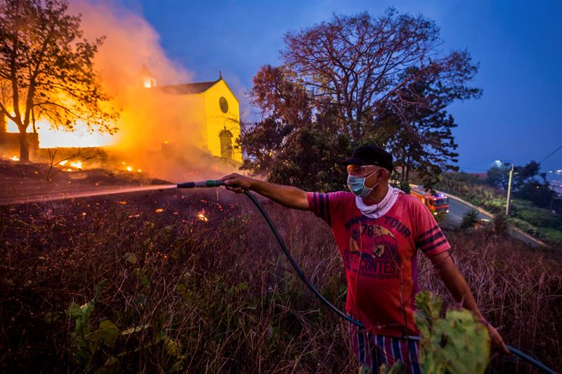 Un residente utiliza una manguera de jardín para ayudar en la extinción de un incendio en Funchal, isla de Madeira (Portugal) 