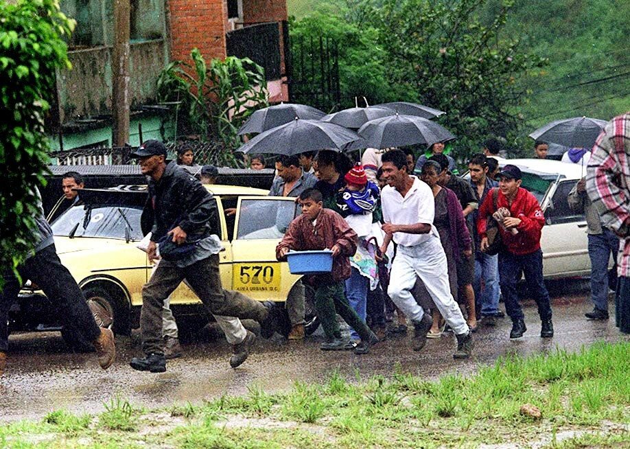 Varias personas corriendo para refugiarse de la fuerza de las lluvias y vientos del huracán Mitch, en  Tegucigalpa (Honduras) en octubre de 1998. 