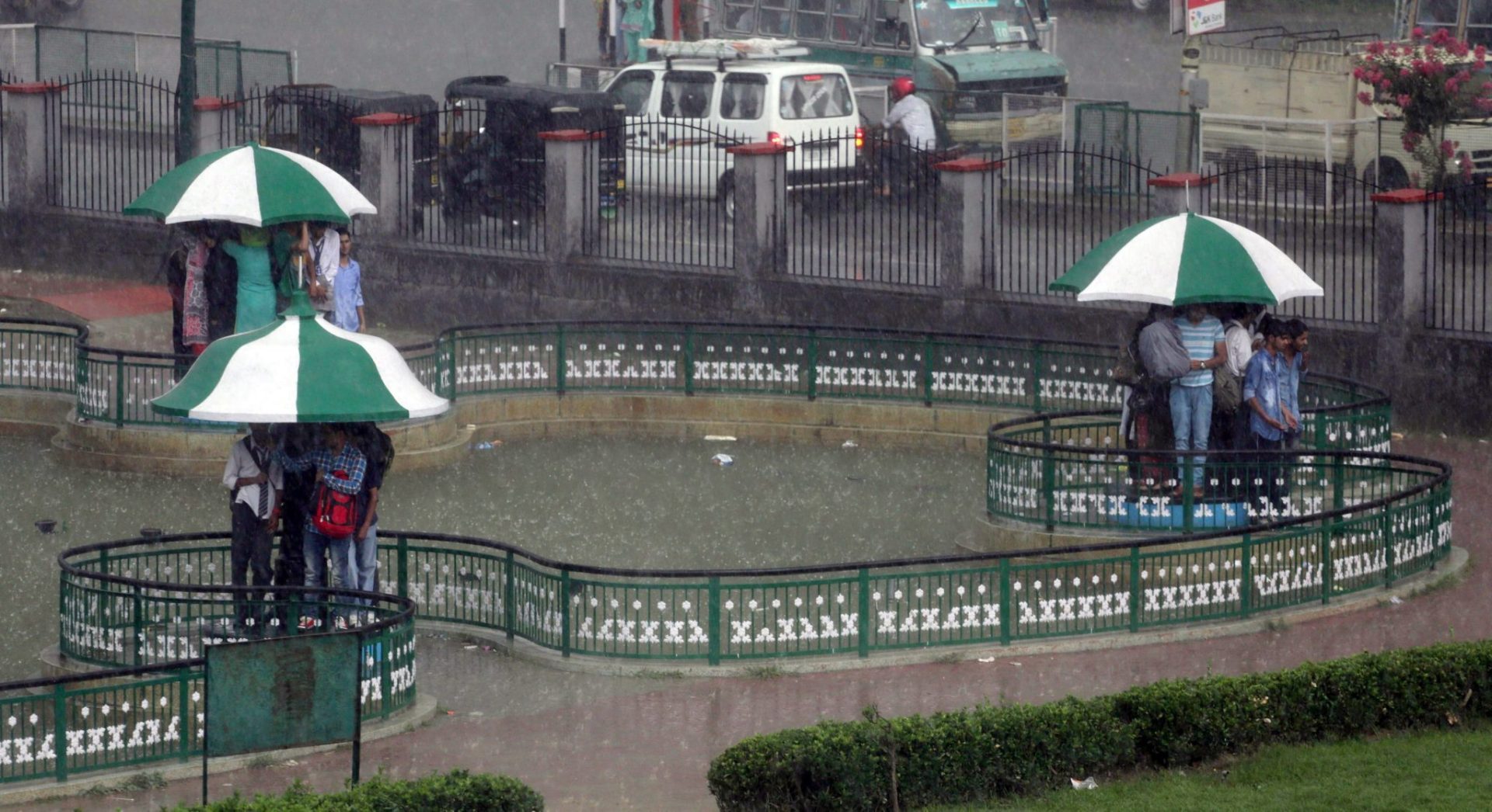 Varias personas se resguardan de la lluvia en Srinagar.