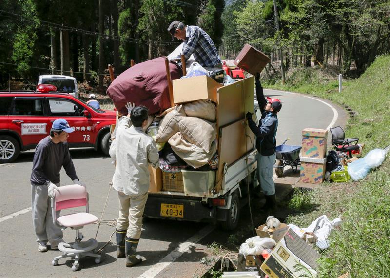 Supervivientes trasladan los enseres rescatados entre los escombros de sus casas.