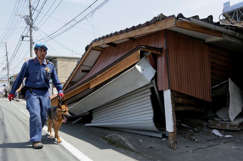 Un policia con un perro caminan ente los escombros del terremoto de 6,5 grados registrado en Mashiki, al suroeste de   Japón.