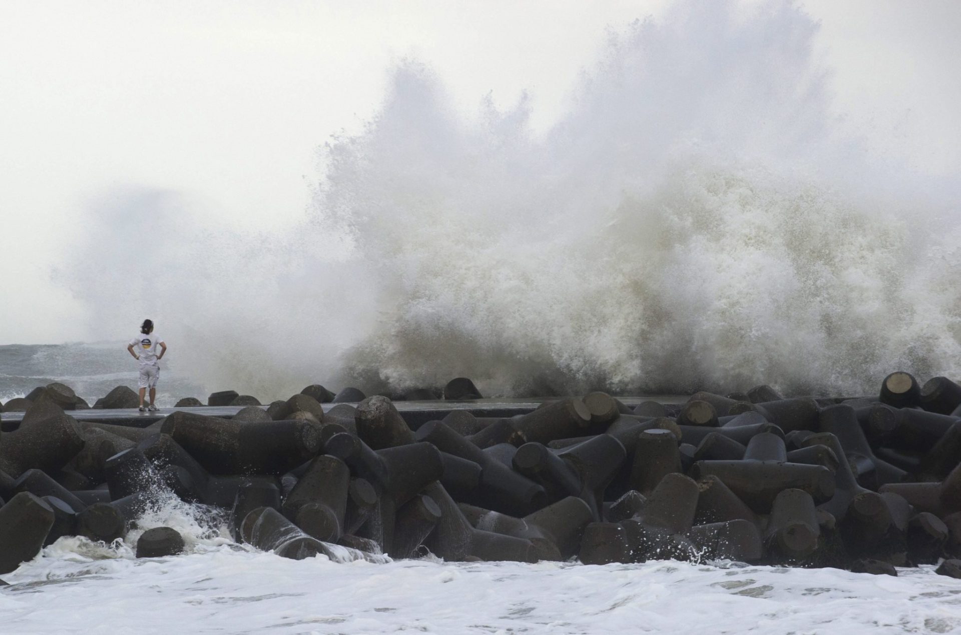 Un surfista observa grandes olas golpeando el rompeolas en Isumi, en la prefectura de Chiba.