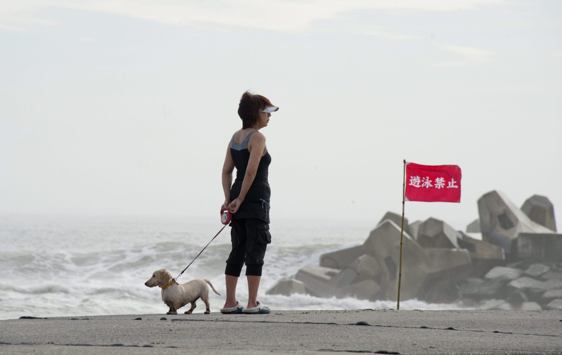 Una mujer observa junto a su perro el estado de la marea a raíz del tifón
