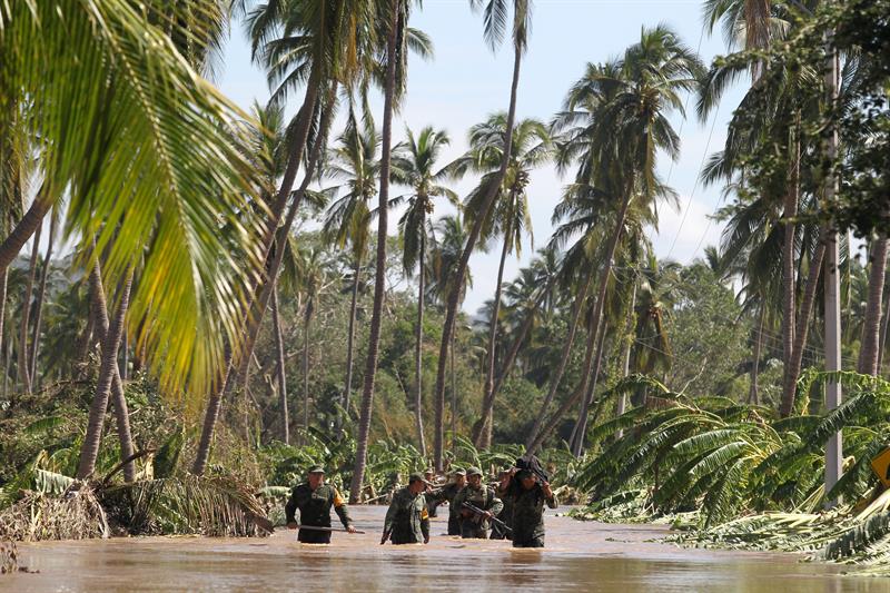 Soldados caminan por una vía inundada tras el paso del huracán Patricia en la comunidad Ranchito (Jalisco). 