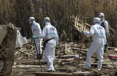 Policías protegidos de la radiación, buscan entre la maleza víctimas del tsunami, en Minamisoma (Fukushima) un mes después del tsunami. 