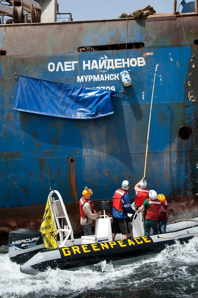 Activistas de Greenpeace retiran la local que tapa el nombre del barco ruso Oleg Naydenov cuando pescaba de forma ilegal en aguas de Senegal, en 2012.