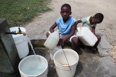 Niños se abastecen de agua en una fuente en San Pedro de Macorís (República Dominicana)