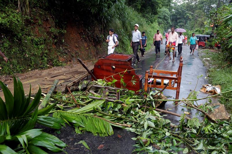 Un grupo de personas camina por una carretera llena de objetos arrastrados durante las lluvias torrenciales en Bulathkohupitiya, provincia de Sabaragamuva, Sri Lanka.
