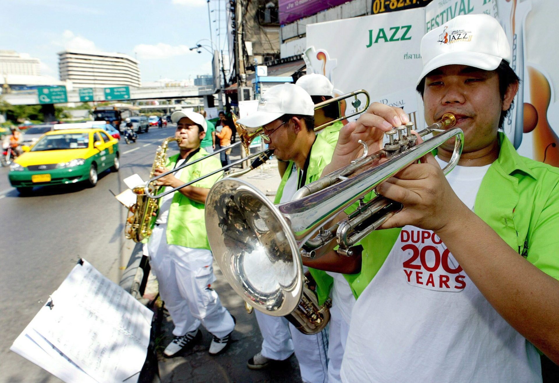 Una banda universitaria de jazz promueve un festival de música, en una calle de Bangkok, 