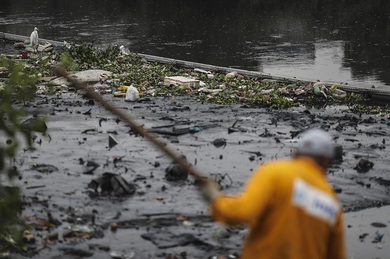 RÍO DE JANEIRO (BRASIL), 20/07/2016.- Dos hombres trabajan en la limpieza del río Meriti, que desemboca en la Bahía de Guanabara, sede de las pruebas de Vela en los Juegos Olímpicos de Río 2016. La Secretaria de Medio Ambiente de Río de Janeiro instaló diversas ecobarreras para contener la basura y evitar que ésta afecte las pruebas olímpicas. EFE/Antonio Lacerda
