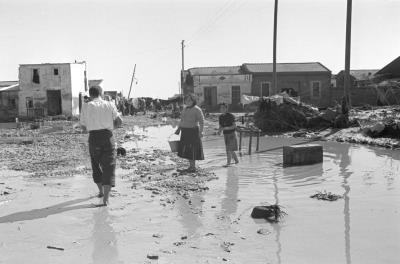 Los vecinos de los barrios más afectados por la riada intentan limpiar de barro sus enseres y levantar sus casas que quedaron devastadas por las inundaciones del 14 de octubre de 1957 tras el desbordamiento del río Turia. 