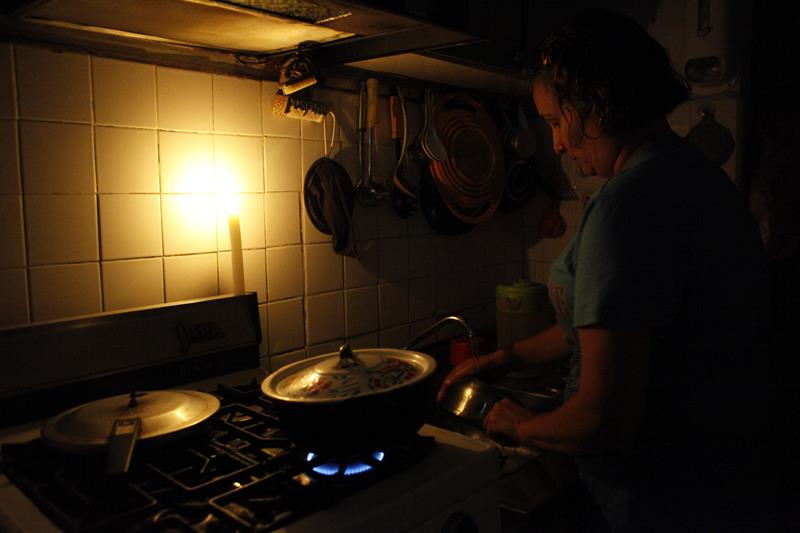 Una vecina de San Cristóbal cocina alumbrada por una vela. La Luz se corta cuatro horas al día. 