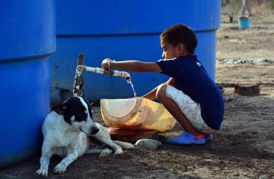 un niño sacando agua de tanques de almacenamiento en Uribia (Colombia)