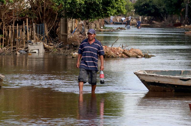 Un hombre camina por una calle que continúa inundada en un barrio.