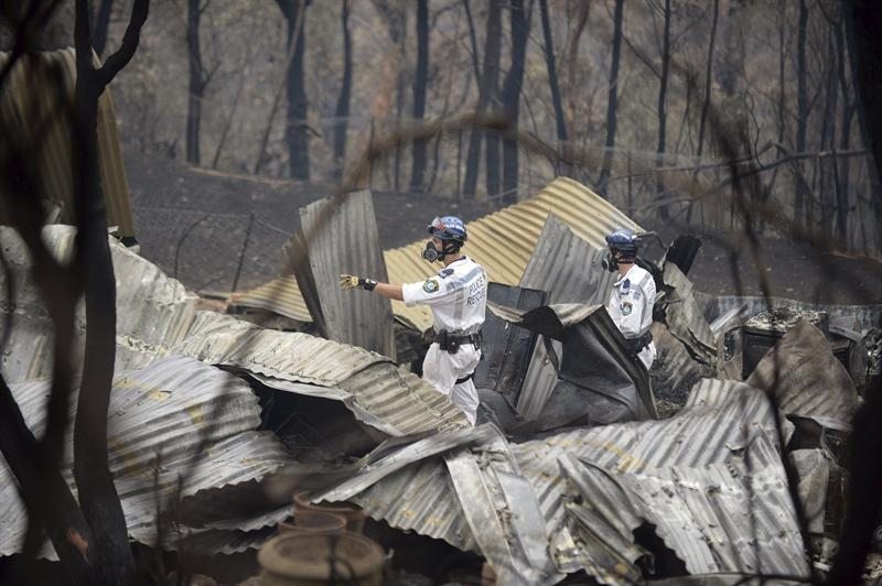 Equipos de rescate inspeccionan los escombros de una propiedad arrasada por un incendio forestal. 
