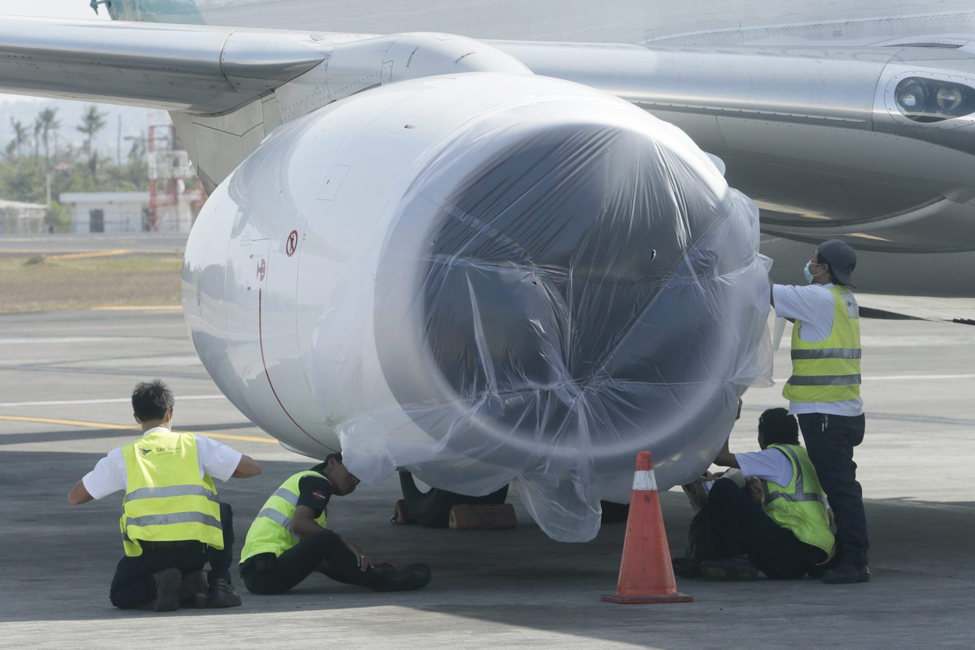 Trabajadores cubren con plásticos los motores de un avión en el aeropuerto de Ngurah Rai en Bali (Indonesia).