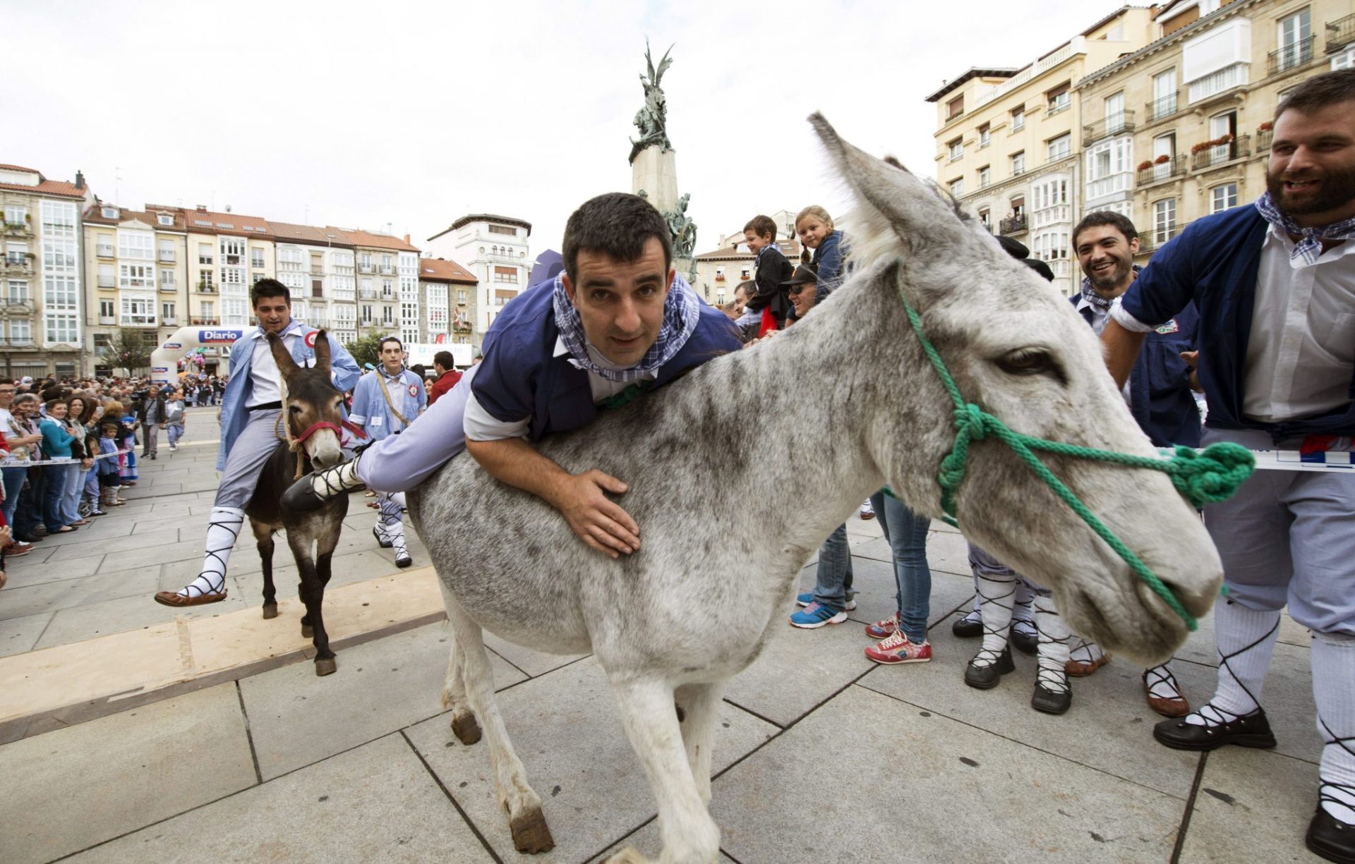 Varios participantes durante la tradicional carrera de burros que tiene lugar en el Día del Blusa y de la Neska como parte de la festividad de Santiago en Vitoria, en una jornada que deja estampas típicas como esta peculiar competición o la de cientos de vitorianos comprando ristras de ajos. EFE/Adrián Ruiz de Hierro