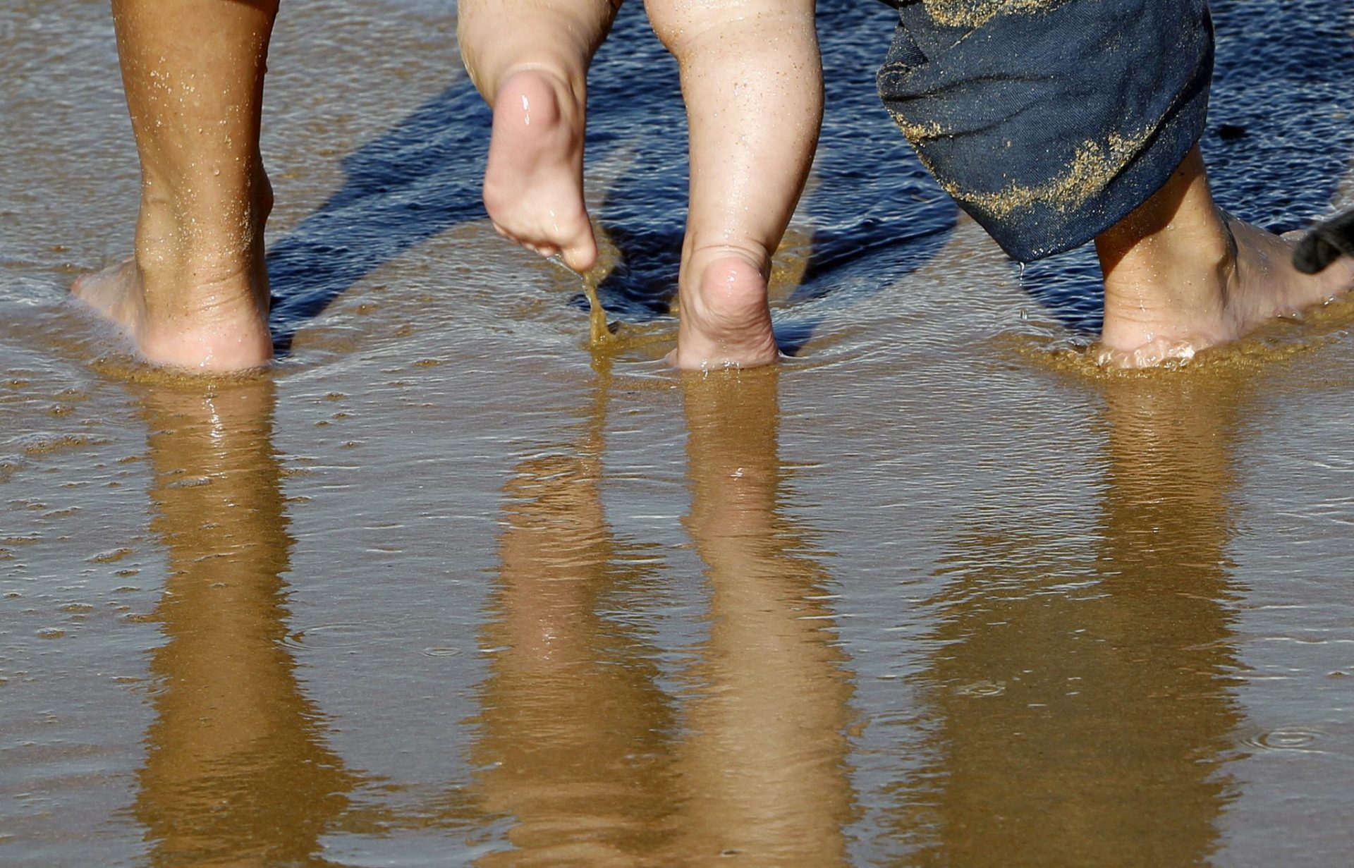 Los pies de una mujer y un bebé en la playa de Ondarreta de San Sebastián